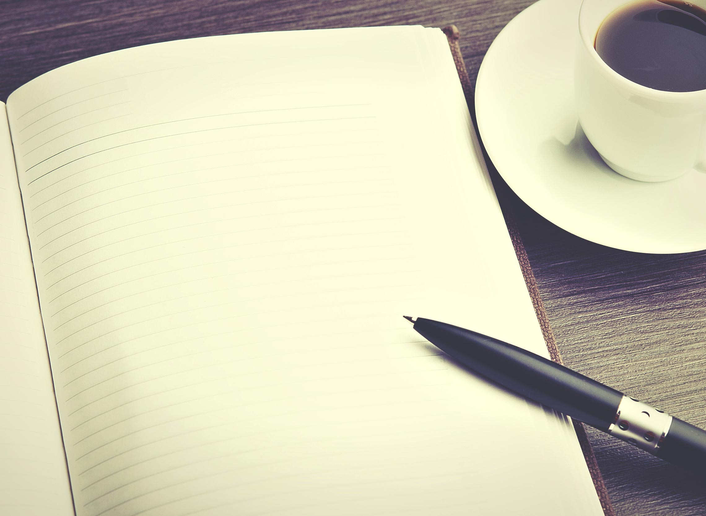 A pen lays on top of a notebook.